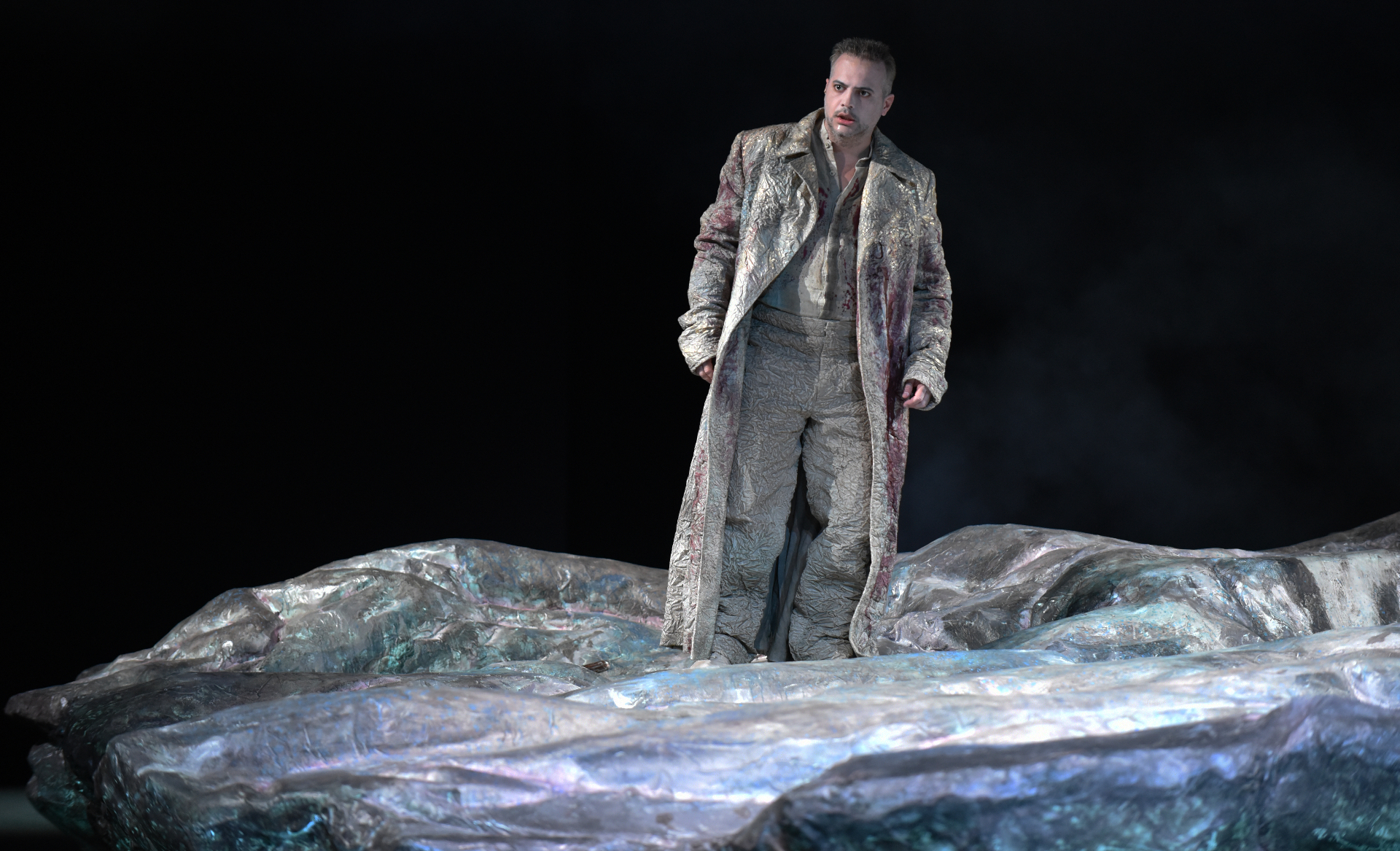 Gaston Rivero on stage in pale costume on a rock